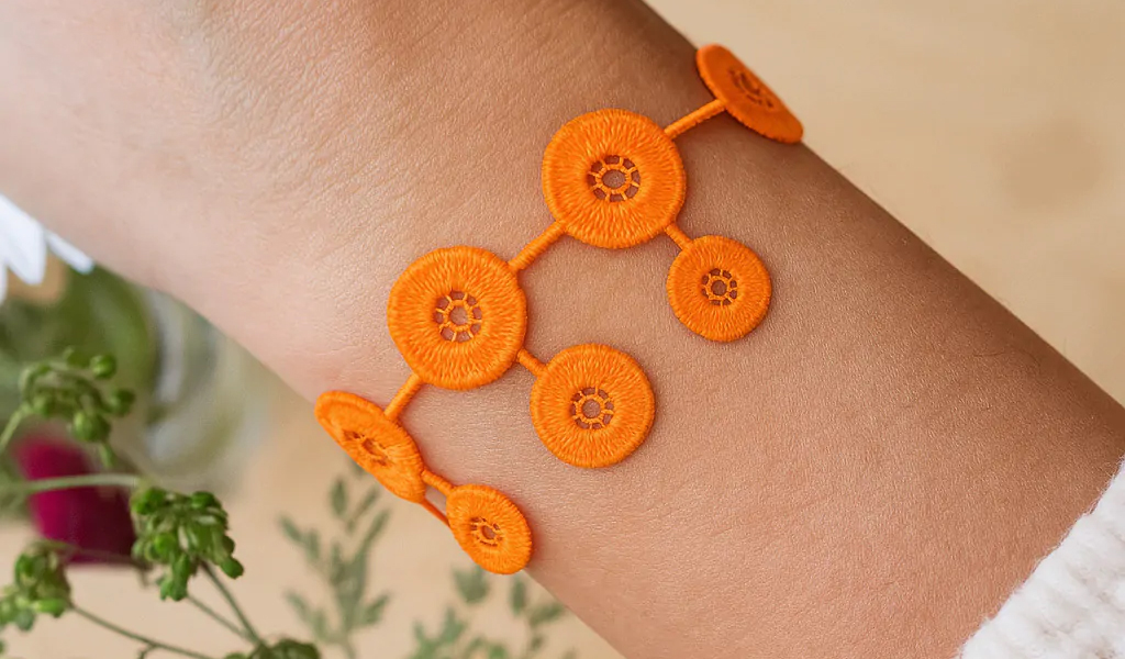 Comment entretenir vos bracelets : conseils pour garder vos bijoux en parfait état Poignet orne d'un bracelet couleur orange ajoure