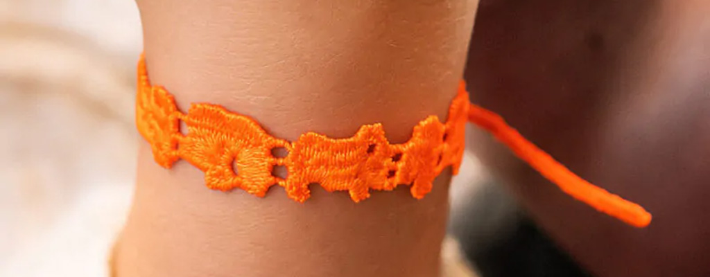 Les bracelets pour les enfants : des idées de cadeaux originales et personnalisées Bracelet en dentelle tressee sur poignet d'enfant de couleur orange