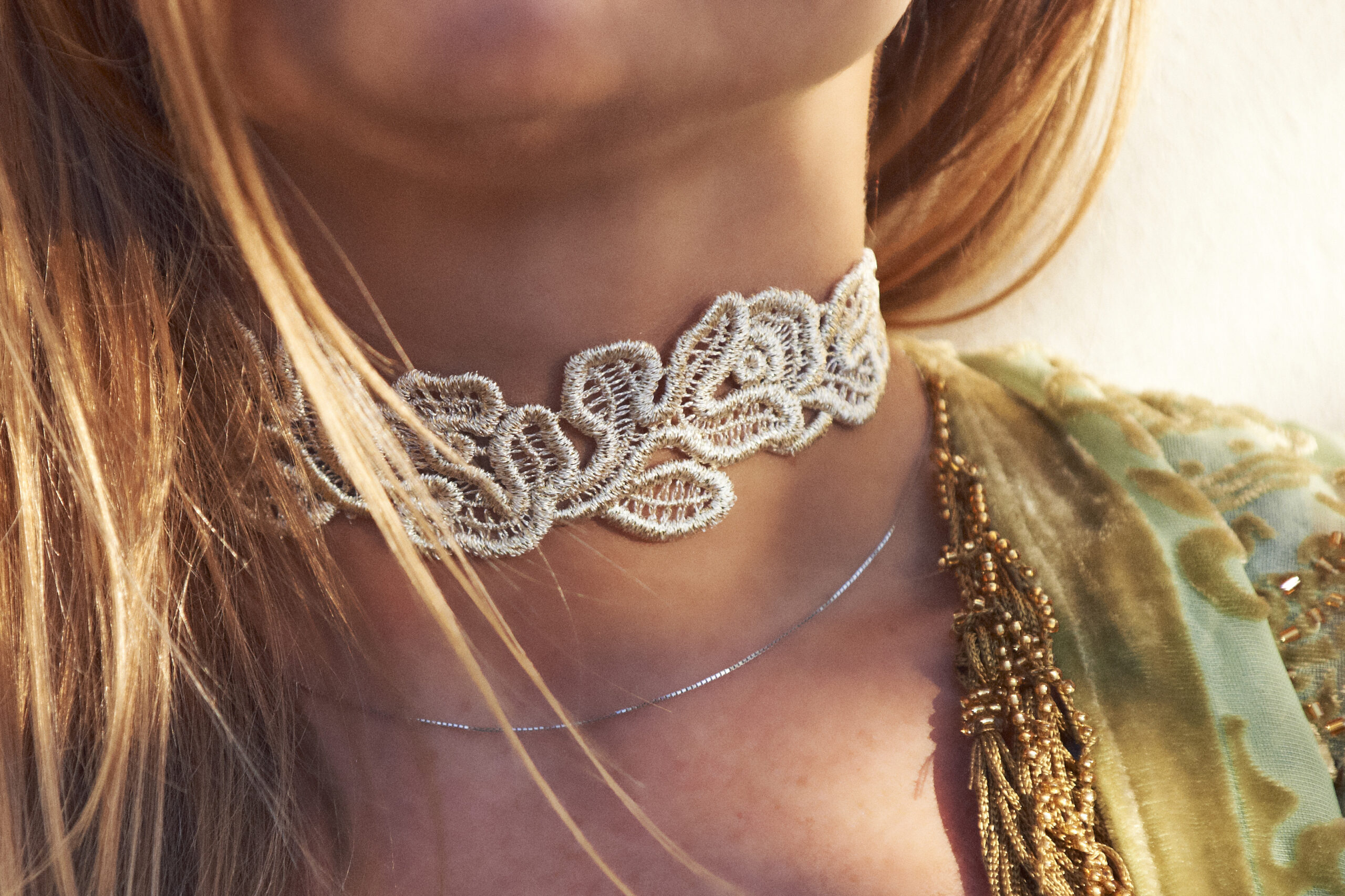 Un collier sous-forme de dentelle porté avec une tenue décolletée