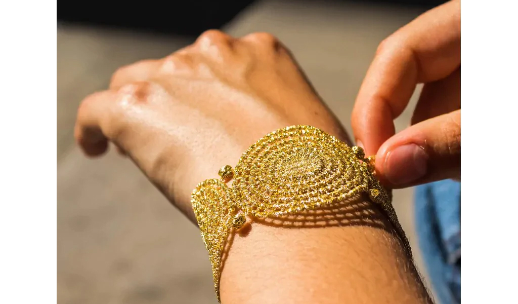 Quel modèle de bracelet femme tendance 2025 choisir ? Bracelet manchette Ethnique en tissu doree sur un poignet