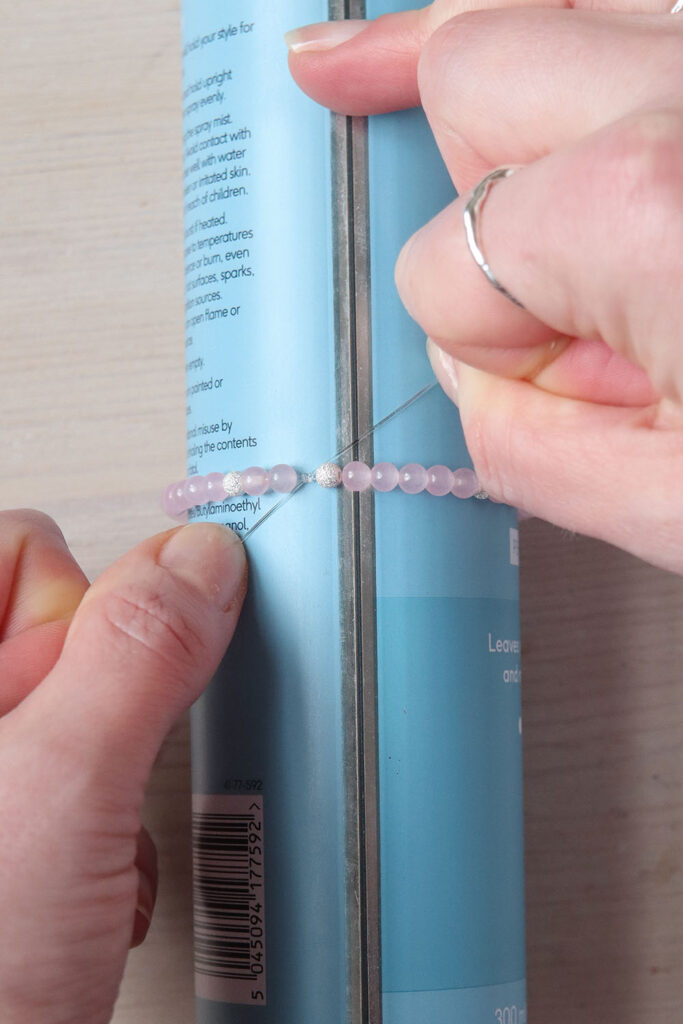 Mains attachant un bracelet de pierres précieuses autour d'une boîte de laque