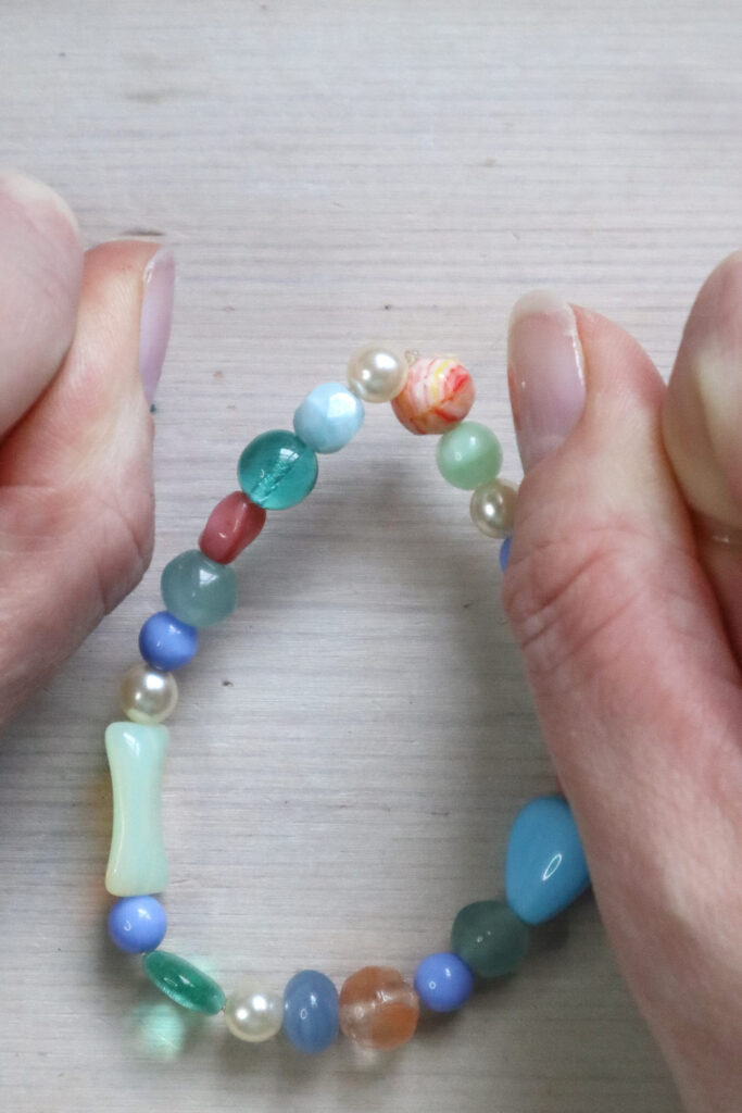 Comment fabriquer un bracelet en perles - mains tirant fermement le nœud d'un bracelet en perles
