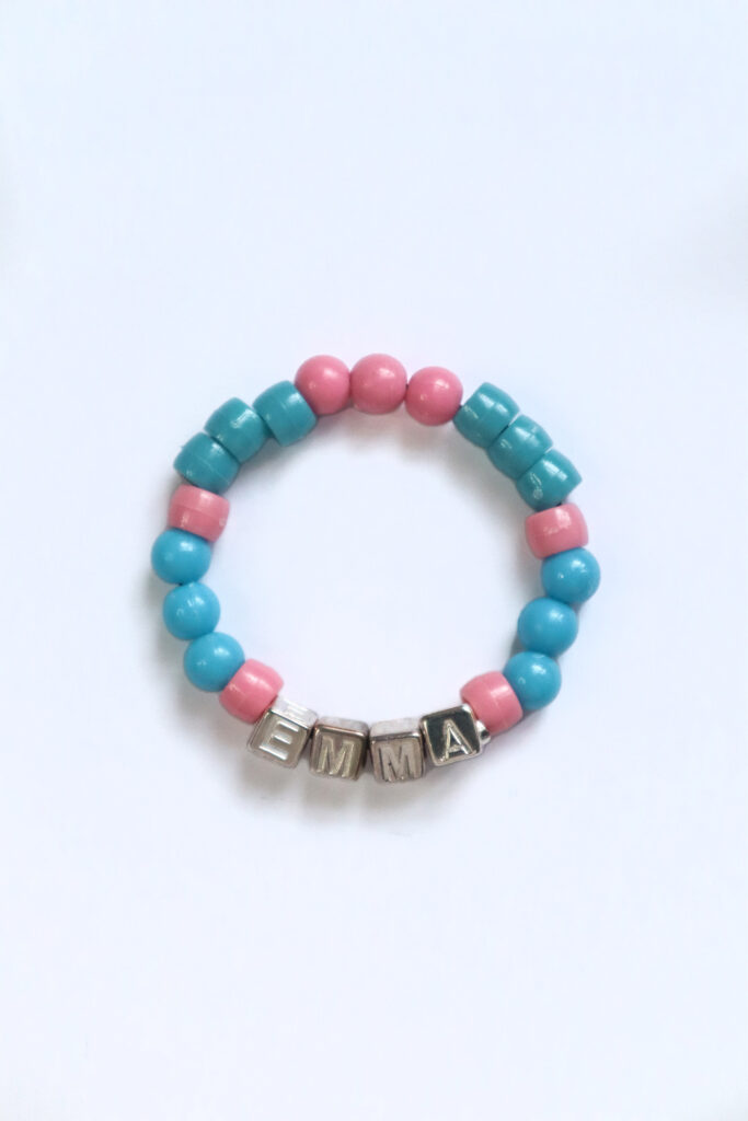 Comment fabriquer un bracelet en perles : un bracelet fini avec des perles en plastique colorées et des perles avec des lettres épelant le nom Emma