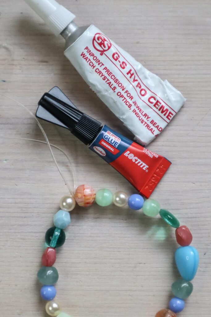 Comment fabriquer un bracelet en perles - bracelet avec des perles de verre colorées, à côté de la superglue et de la colle GS Hypo Cement qui peut être utilisée pour sécuriser les nœuds